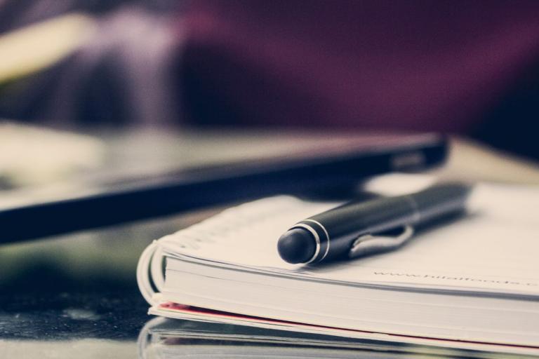 A note pad with a pen sitting on the top