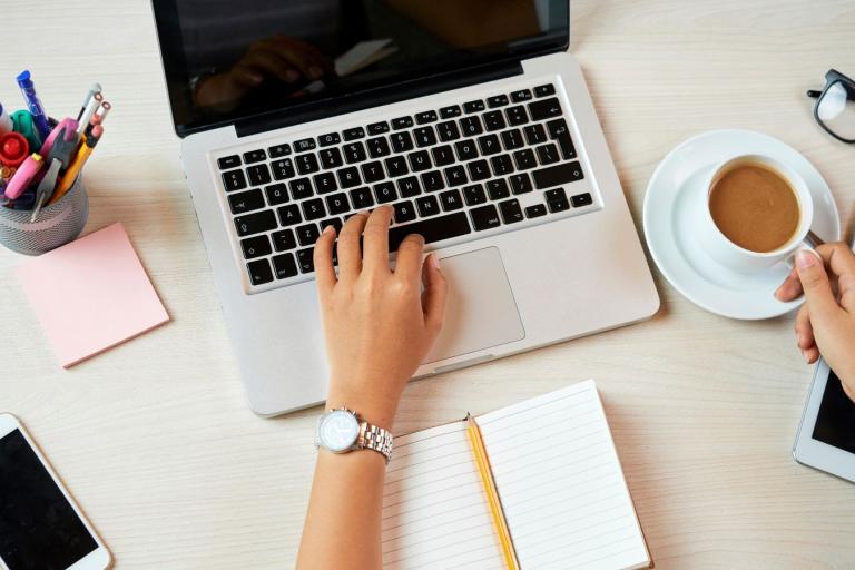 Person using a laptop and drinking a beverage