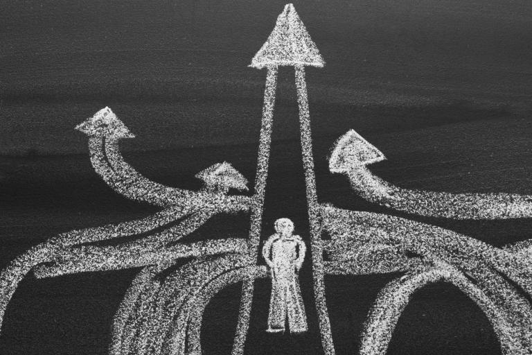 A blackboard with a drawing of a young person choosing to take different paths