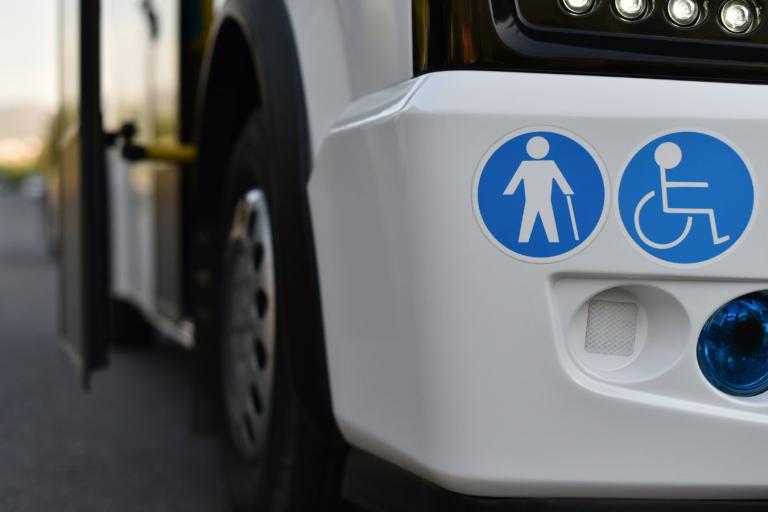 A white bus with disabled stickers on it