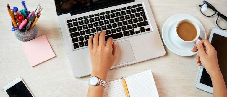 Person using a laptop and drinking a beverage